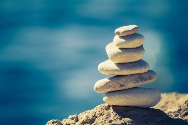 Close-up of white pebbles stack over blue sea